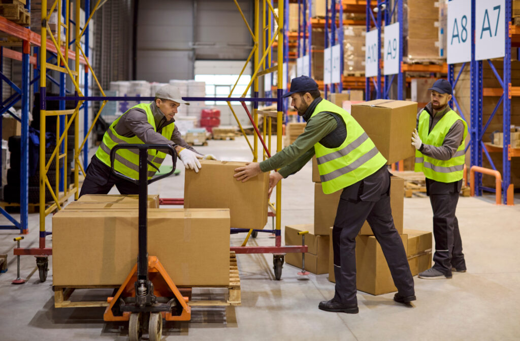 Workers in warehouse loading boxes on pallet.